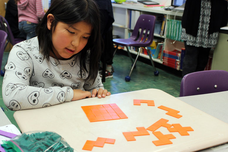 A Donald Young student proudly creates a square using pentominoes