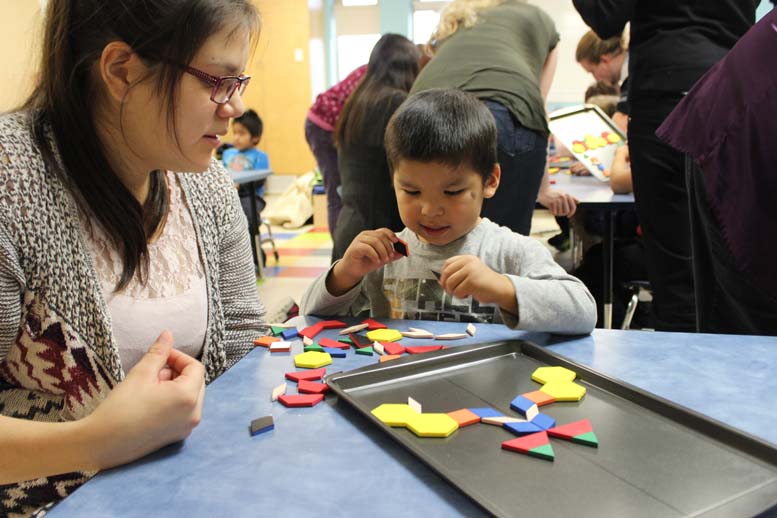 Aroland educator and a student playing with pattern blocks