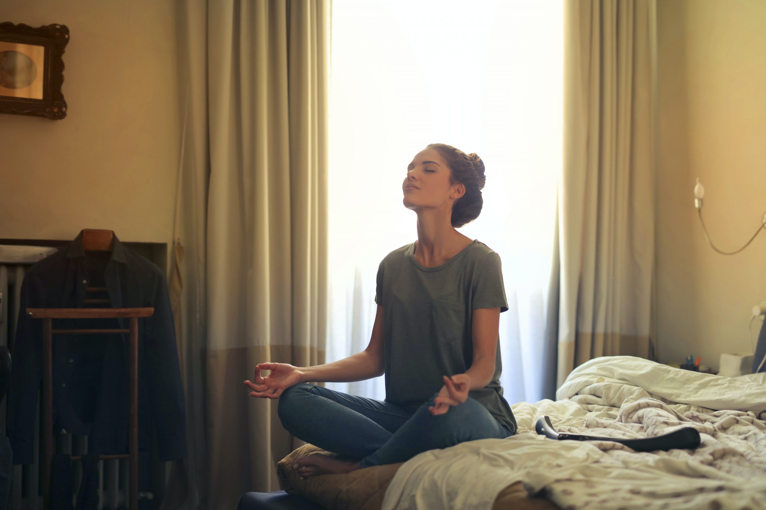 Person sitting on bed meditating